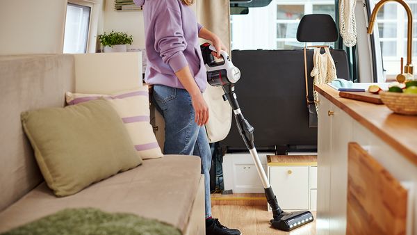 Eine Person saugt mit dem Unlimited 7 Akku-Staubsauger von Bosch den Fußboden eines Wohnmobils.