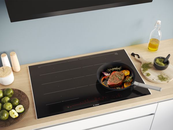 Piano cottura a induzione Bosch con padella e bistecca in cottura