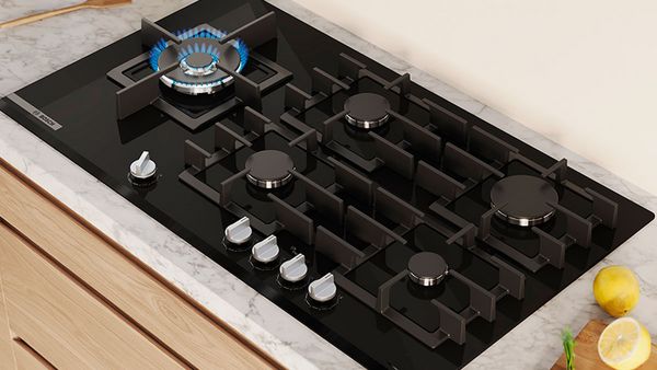 Gros plan d'un brûleur gaz avec flammes bleues, entouré de grilles en fonte noires.