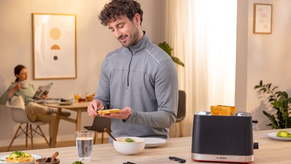 Person buttering toast with Bosch toaster to the side