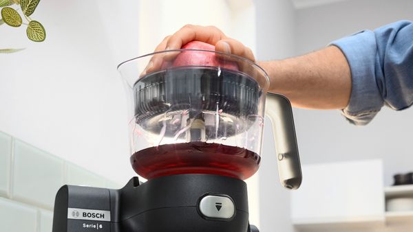 Person squeezing juice with Series 6 citrus press attachment.
