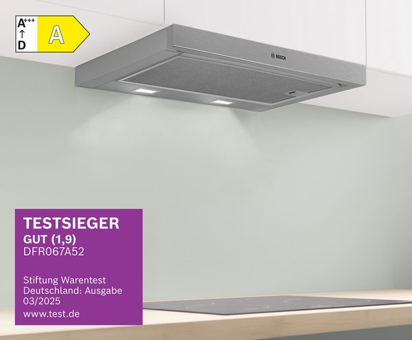 Hände laden einen 3D-Drucker mit roter Filamentkartusche auf einem Holztisch vor einer gefliesten Wand.