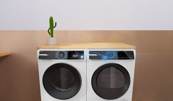 Ein wei&szlig;es Bosch‑Duo aus Waschmaschine und Trockner steht auf einer Holzarbeitsplatte.