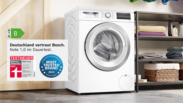 Waschmaschine umgeben von Handtüchern und Ablagen.