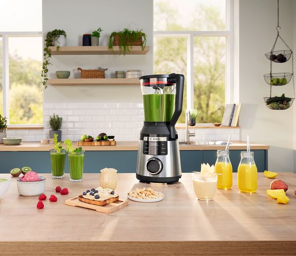 Eine moderne Küche mit einem Bosch-Mixer auf einer Holzarbeitsplatte, umgeben von frischen Zutaten