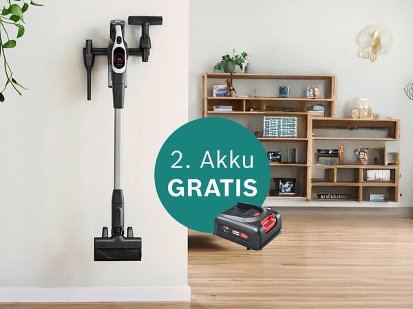 An einer Wand lehnt ein kabelloser Staubsauger, der zusätzlich als Akku angeboten wird, und der die wichtigsten Reinigungsutensilien für den Haushalt hervorhebt.