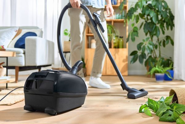 A bagged cylinder vacuum sucks up visible dirt on the floor.