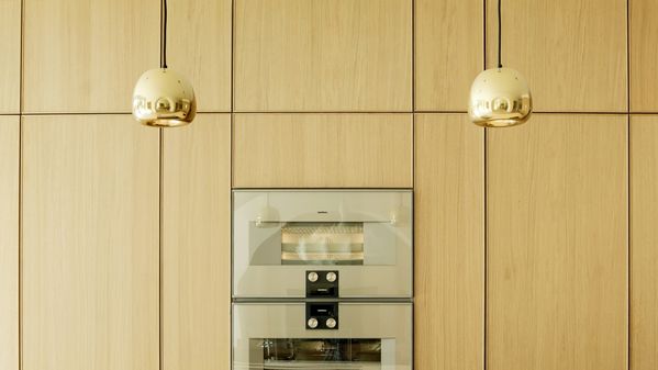 Close-up view of the White Oak finish, Gaggenau 400 series appliances and pendant lighting