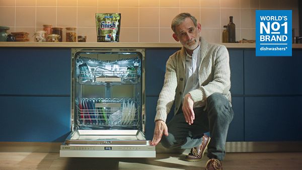 Man naast een open vaatwasser.