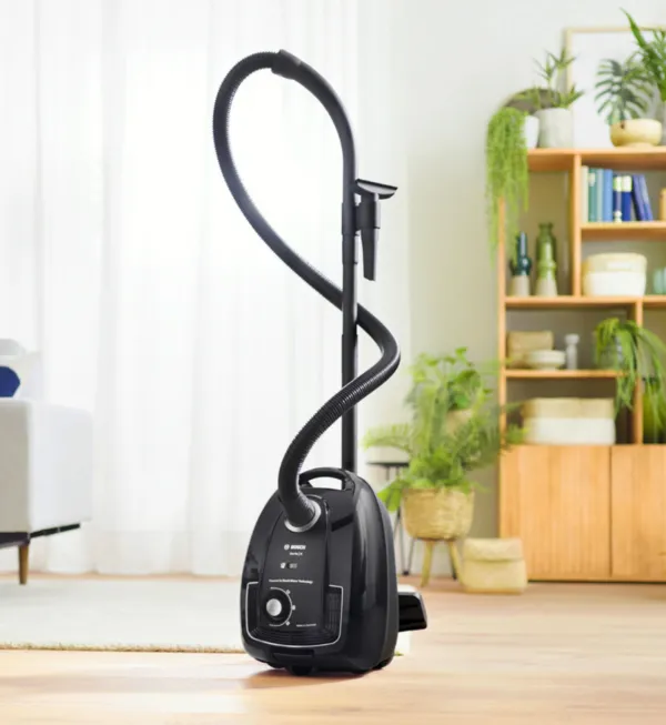 A bagged cylinder vacuum sucks up visible dirt on the floor.