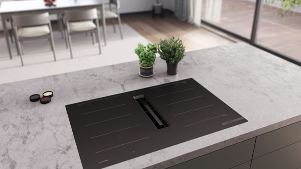 Matzwarte kookplaat in wit marmeren werkblad 