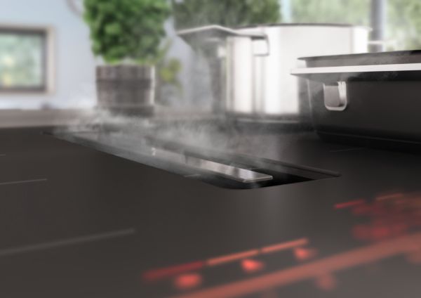 Inductiekookplaat met geïntegreerde afzuigkap zuigt kookdampen af tijdens het koken