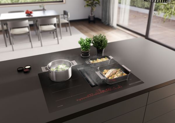 Inductiekookplaat met geïntegreerde afzuigkap in gebruik met pan en braadpan voor het bereiden van maaltijd