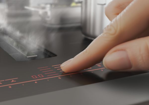 Hand bedient rode digitale touchscreen bediening van inductiekookplaat in moderne keuken
