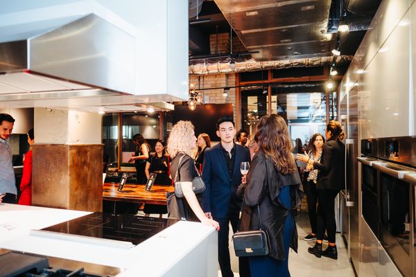 Guests gather at a stylish Bosch kitchen event, engaging in conversation amid modern appliances and décor.