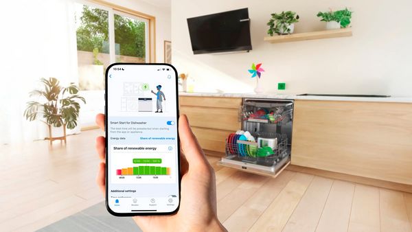 Een smartphone met de Bosch app toont hoeveel hernieuwbare energie gebruikt werd door de vaatwasser die op de achtergrond staat. 