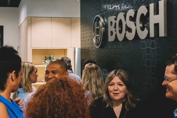 Group of people networking at a Bosch event, with a stylish kitchen background and the Bosch logo visible.