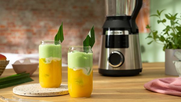Zwei Gläser mit Pandan-Mangosmoothie stehen vor einem VitaPower Serie 6 Standmixer von Bosch.