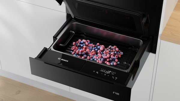       Eine Bosch-Schublade, die ein Metalltablett mit bunten gefrorenen Beeren zeigt.     