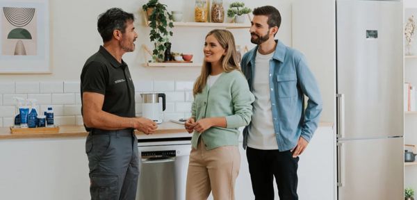 Three people stand in the Bosch Home of Innovation showroom kitchen, featuring a modern refrigerator.  