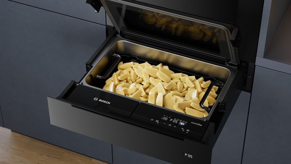 Kartoffelspalten für selbstgemachte Pommes Frites in einer geöffneten Bosch Dampfgarer-Schublade.