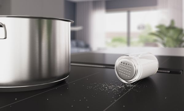 Close-up van een hand die de slider van een Matt Design-kookplaat bedient.