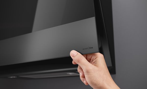 
       Close-up van hand die de hoek van de Bosch Matt Design schuine afzuigkap afveegt.
      