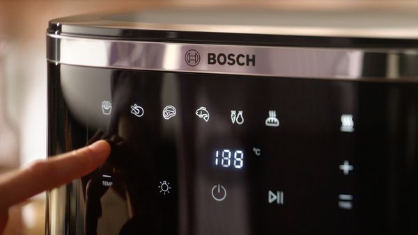 Ein Air Fryer von Bosch, der von einer Person bedient wird.