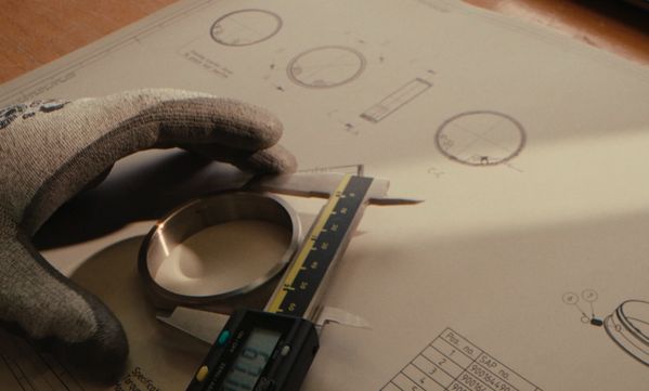 Gloved hand using digital vernier calipers to measure a Gaggenau control ring