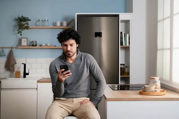Encimera, teléfono inteligente y café en escritorio de madera con obras de arte enmarcadas en pared y ventana en fondo.