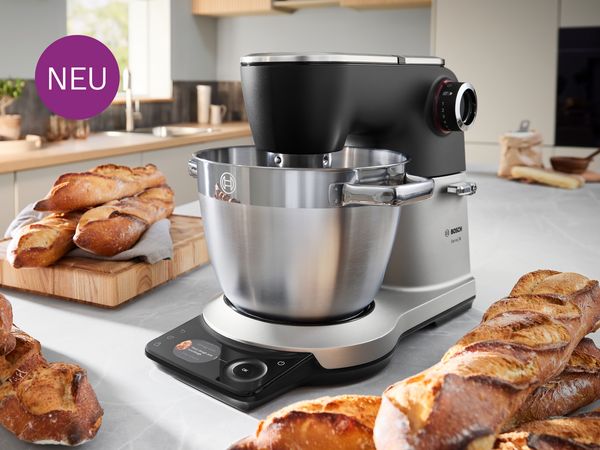 Die Bosch Küchenmaschine Serie 8 steht neben frisch gebackenem Brot in einer Küche.