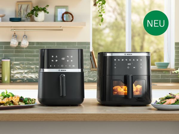 Zwei Bosch Heißluftfritteusen stehen nebeneinander auf einer Arbeitsplatte in einer modernen Küche.