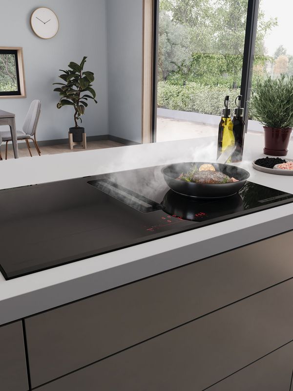 Plaque de cuisson aspirante avec po&ecirc;le remplie d'aliments qui cuisent