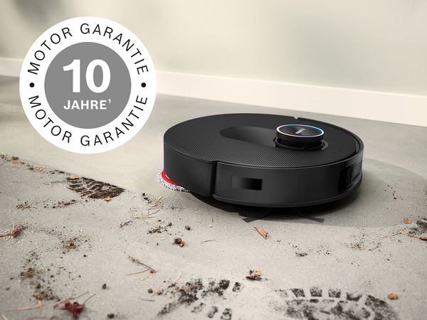 Spotless reinigt Schlamm von weißen Fliesen, mit einem 10 Jahre Motor-Garantie-Abzeichen in der oberen linken Ecke.