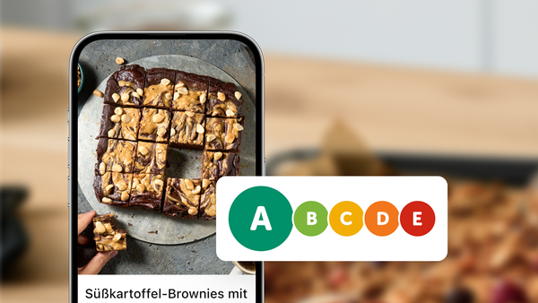 Ein Smartphone zeigt ein Süßkartoffel-Brownie Rezept vor einem verschwommenen Küchen-Hintergrund neben einer Nutri Score Tabelle.