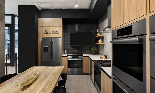 Guests socialize at a Bosch event, enjoying drinks and engaging around a modern kitchen setup.