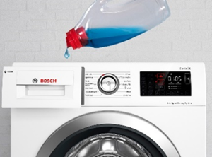 A bottle of liquid detergent pouring blue liquid into the dispenser drawer of a white Bosch washing machine with a control panel and round door