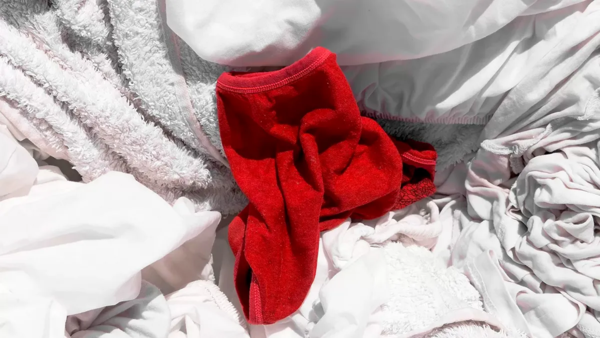 A single red garment lies among a pile of white laundry.