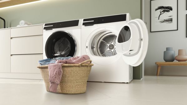 Moderner Hauswirtschaftsraum mit Waschmaschine, Trockner, Regal mit gefalteten Handtüchern und Korb mit bunter Wäsche