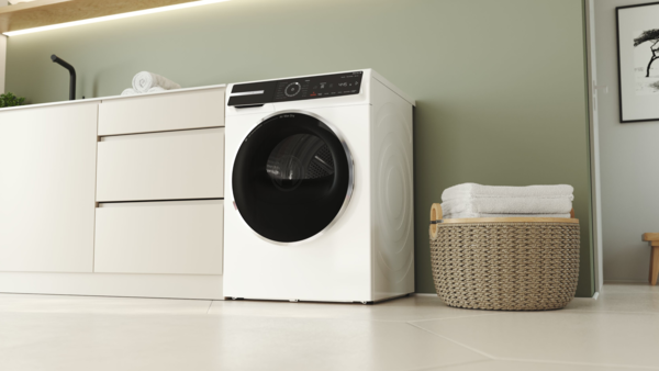 Eine freistehende Waschmaschine in einem Badezimmer, auf der sich ein paar gestapelte Handtücher befinden.