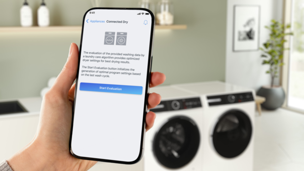 Zwei T-Shirts mit WLAN-Symbol über einer Waschmaschine und einem Trockner.