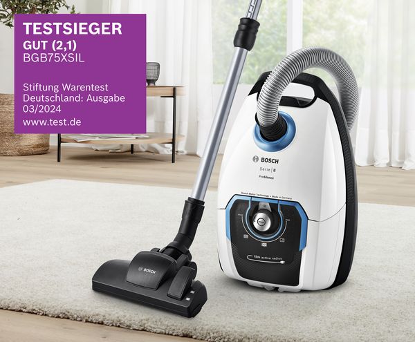 Ein Bosch Series 8 Staubsauger auf einem weißen Teppich, der sein preisgekröntes Design und seine Funktionen zusammen mit einem Testsieger-Label präsentiert. 