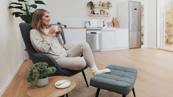 Une cuisine blanche avec un four et une machine à café Bosch encastrés en arrière-plan, et un filtre à eau Brita posé à côté d’une tasse de café sur le plan de travail. 