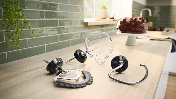 Schlagbesen, Knethaken und flexibler Rührbesen auf einer Küchenarbeitsplatte.