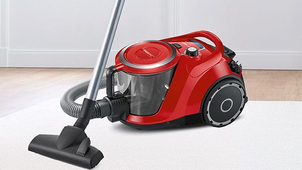 A dark blue bagless vacuum on a living room rug.