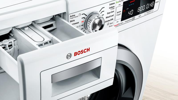 A close-up view of a white Bosch front-loading washing machine with its detergent dispenser drawer pulled open