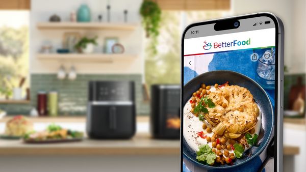 На екрана на мобилен телефон се показва приложението Bosch better food. На заден план е кухненски плот с Bosch Air Fryer.