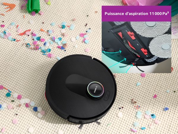 Spotless sur un tapis blanc, nettoyant un chemin &agrave; travers les confettis, mettant en avant sa puissance d'aspiration.