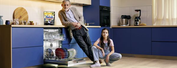 Eine moderne Küchenszene mit einem Geschirrspüler, der mit bunten Tellern und Gläsern beladen ist, ergänzt durch Küchengeräte und Dekoration.