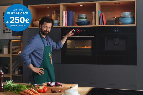 Čovjek stoji ispred dvije ugradbene pećnice u kuhinji.